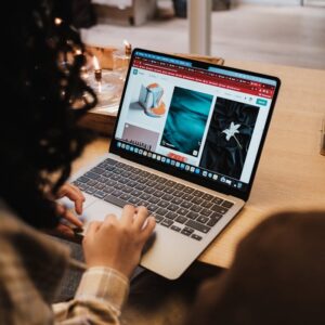 Curly-haired woman browsing online stores on a laptop while seated indoors.