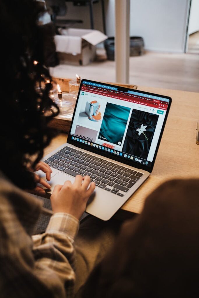 Curly-haired woman browsing online stores on a laptop while seated indoors.