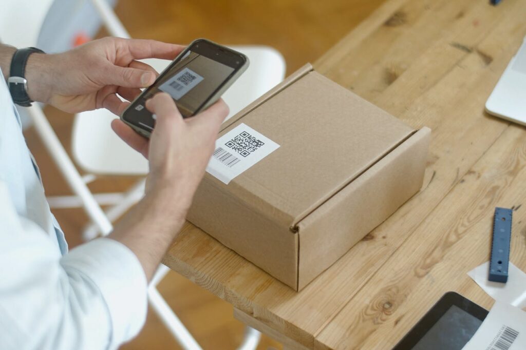 A person uses a smartphone to scan a QR code on a package in an online store setting.